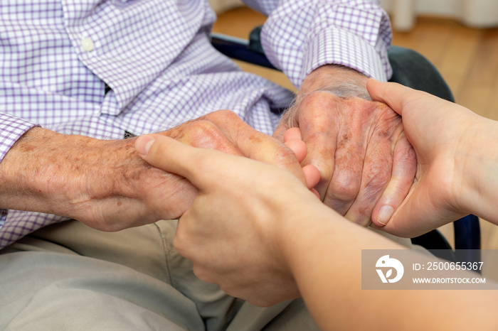 Detail of young and old human hands holding each other.