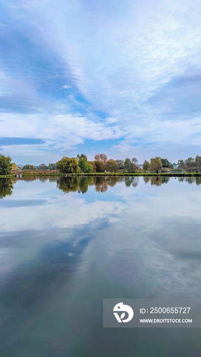 Sunny day on the perfect lake. Autumn lake with reflection on the water. Cloudy sky in the sunny day