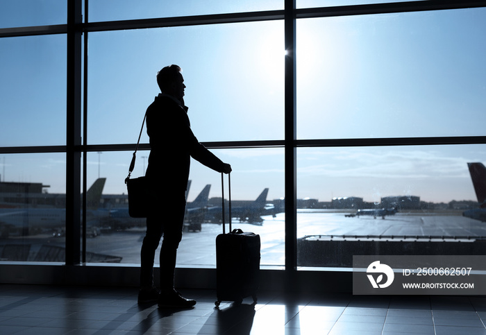 Businessman standing in airport and talking on phone