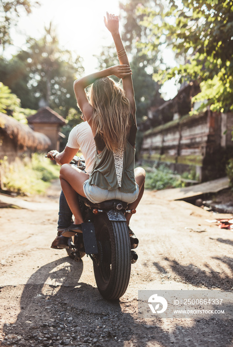 Young couple riding motorcycle on rural road