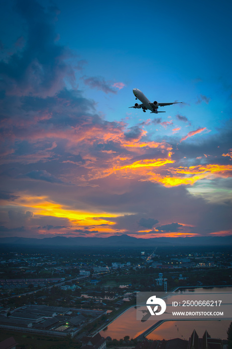日落时，飞机在天空和城市上空飞行的剪影。