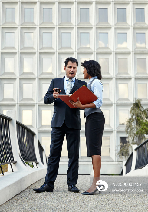 Business people standing talking holding red file and smartphone