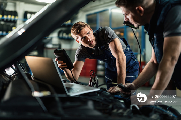 Auto mechanics talking while working on car diagnostic in repair shop.