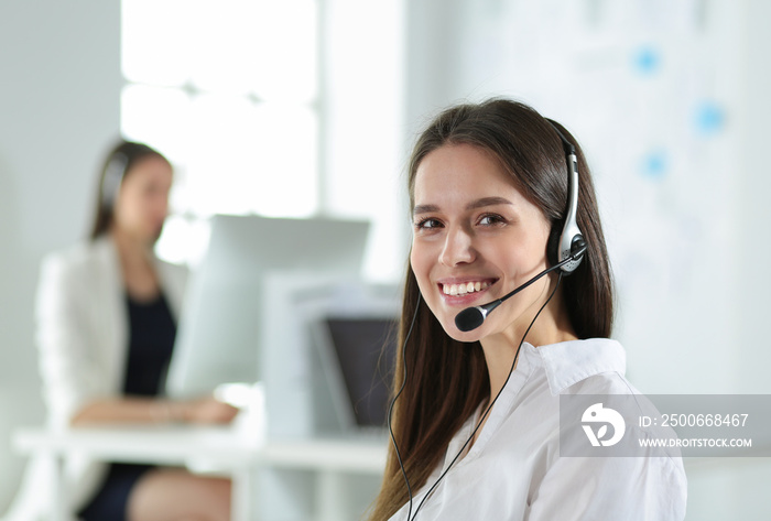 Smiling businesswoman or helpline operator with headset and computer at office