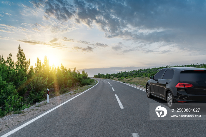 Black car on a scenic road. Car on the road surrounded by a magnificent natural landscape.