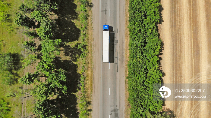 Aerial. Blue truck on a road between fields. Transport logistics background.