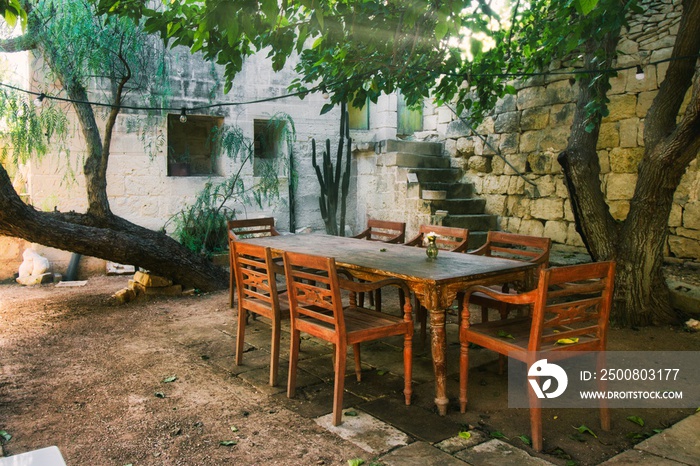 Old-fashioned wooden dining table and chairs outdoors in a Mediterranean garden