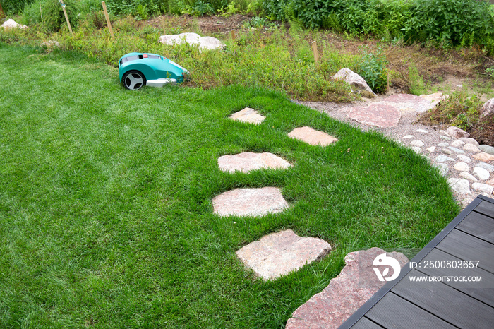 A robotic lawn mower working on a green grass field.