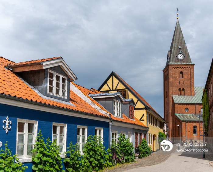 neighborhood street in historic Aalborg city center with colorful houses and the Church of Our Lady in the background