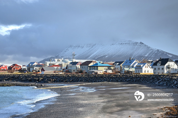 Akranes, Iceland, February 28, 2012: Colorful houses next to the beach with mountains partially obscured by clouds in the background