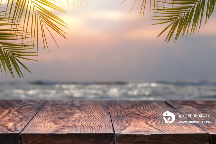 Empty wooden table and palm leafs on a background of beach blurred.