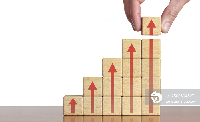 Der Trend zeigt eindeutig nach oben - Businessmann legt auf den Holz-Chart noch einen Würfel darauf