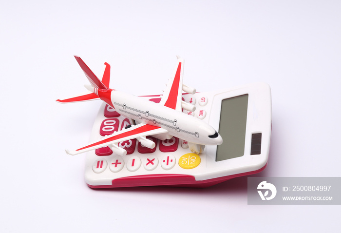 Calculator with a model of a passenger plane on a white background. Travel concept