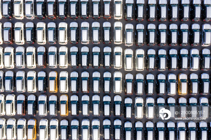 Aerial top view new cars lined up in the port for import export business logistic and transportation by ship in the open sea. New cars from the car factory parked at the port