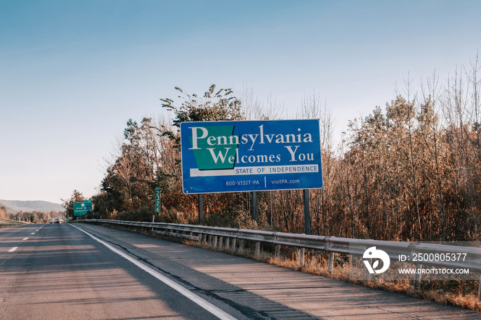 Street road sign saying Pennsylvania Welcomes You. Street road city town state sign in USA. Blue street sign with English text for vehicle drivers on highway outdoors.