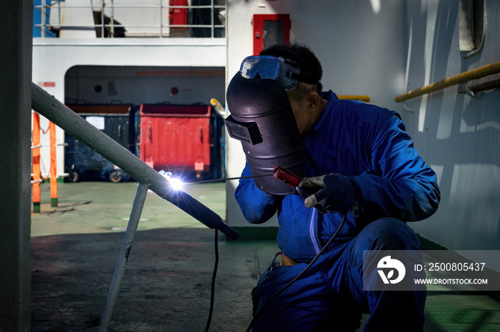 Welder is Welding process with sparks by MIG torch on board a ship