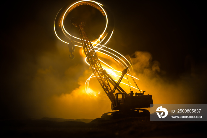 Abstract Industrial background with construction crane silhouette over amazing night sky with fog and backlight. Tower crane against the foggy sky at night.