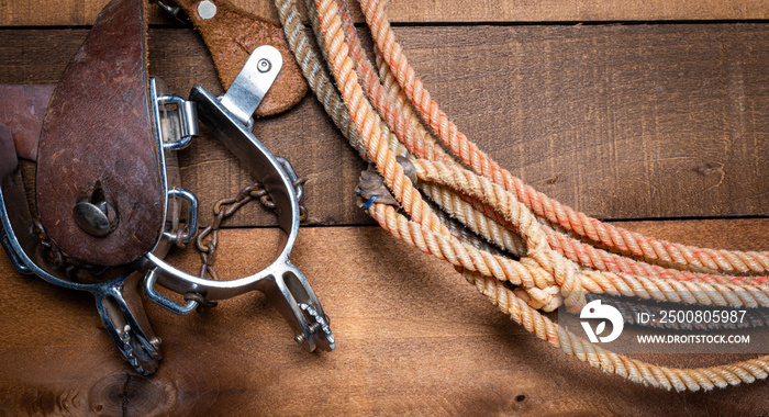 American Cowboy Items incluing a lasso spurs and a traditional straw hat on a wood plank background