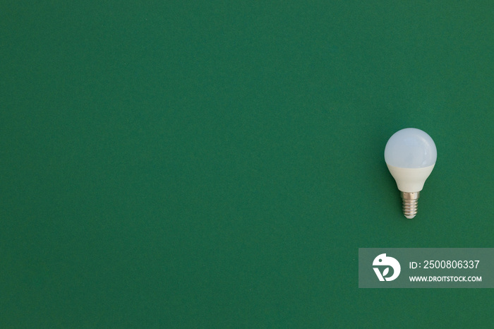 LED light bulb lies on a pastel green background. Energy saving concept. Minimalism, top view