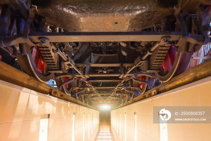 Wheels of an old locomotive train locomotive from below. View of the engine undercarriage from the bottom of the inspection pit.