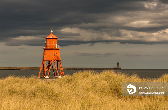 The old, red, wooden Herd Groyne Lighthouse in South Shields, stands out against the cloudy sky