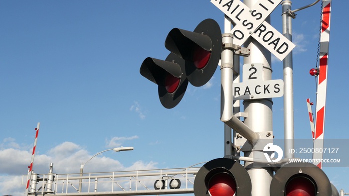 Level crossing warning signal in USA. Crossbuck notice and red traffic light on rail road intersection in California. Railway transportation safety symbol. Caution sign about hazard and train track