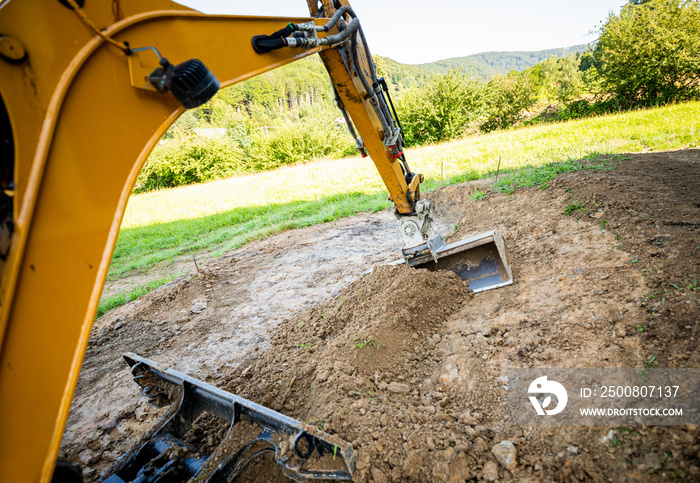 Mini excavator digging preparing ground under home garden