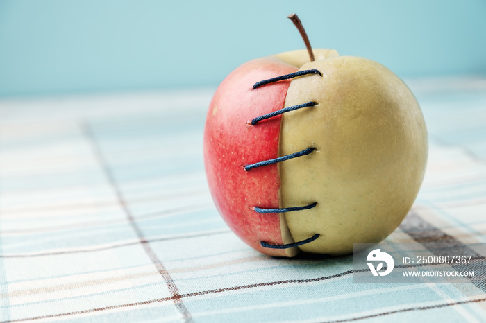 Two different halves of apple connected by thread