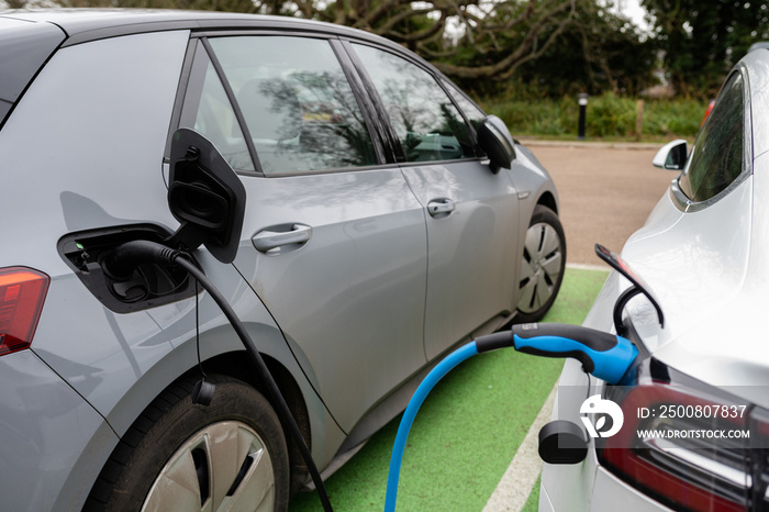 Electric cars charging at plug in charge station in a public car park in Suffolk, UK