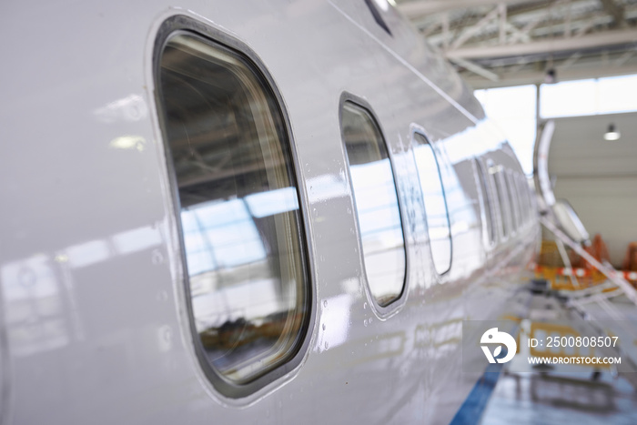 Closeup view on illuminators of passenger aircraft standing on parking place at airport hangar.