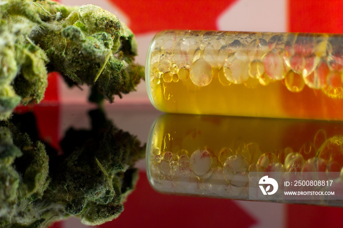 Medical Oil Cannabis - marijuana oil, resin and flowers with Canada flag on the mirror black background.