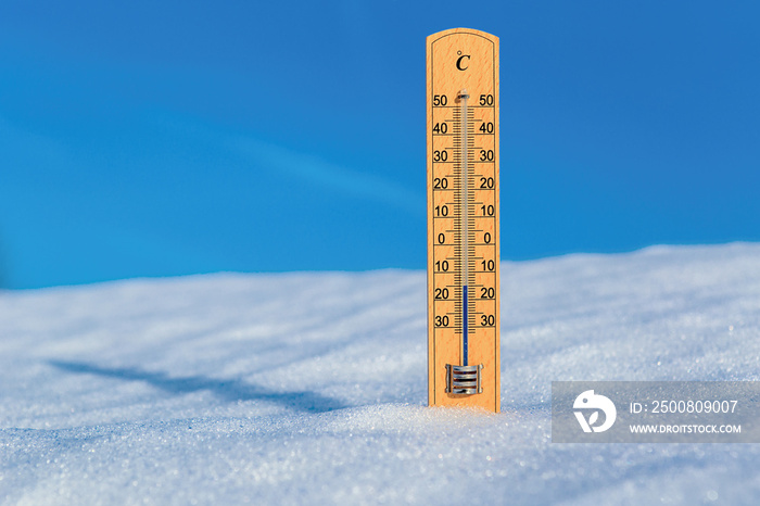 Thermometer in snow against blue sky. Thermometer display minus 15 degrees celsius