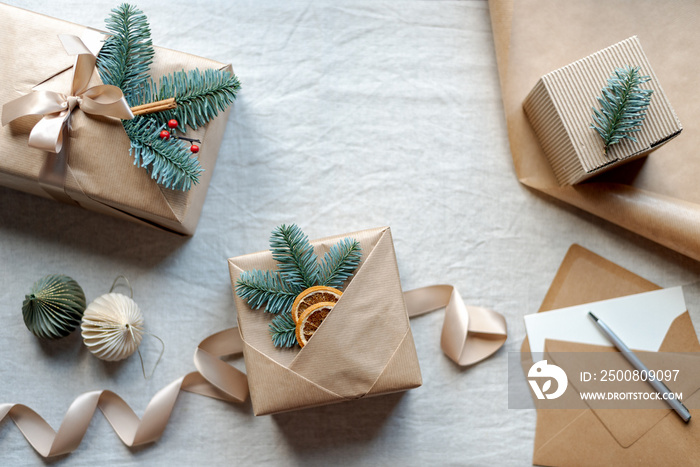 Beautifully wrapped Christmas gifts with natural decor on the top lie on the table.