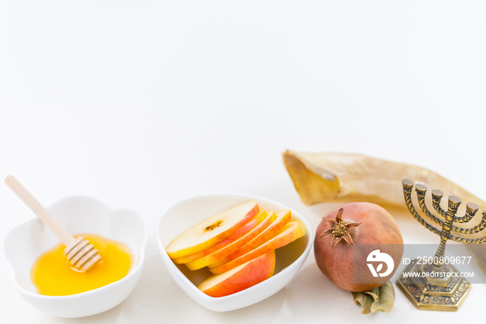 Rosh Hashana symbols, jewish new year. Apple and honey, pomegranates, Shofar ram’s horn, on white table. Selective focus.