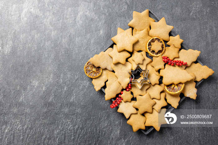 Christmas traditional gingerbread cookies on a plate with decoration on dark background. Top view. Copy space.