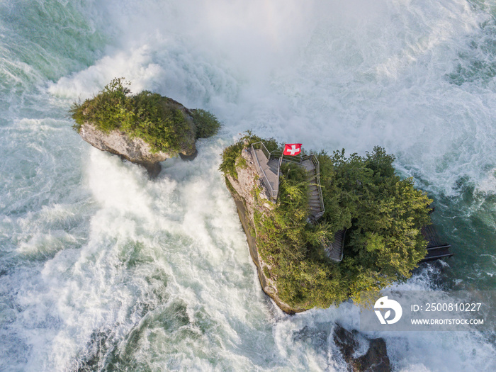 Aerial view of rocks in Rhine falls water cascade near Schaffhausen with swiss flag in Switzerland