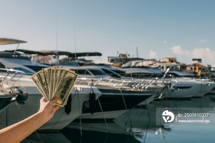 cropped view of woman holding dollar banknotes near yachts in mediterranean sea