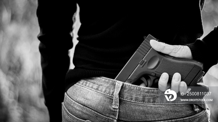 A woman hidden a gun the back. - violence and crime concept.