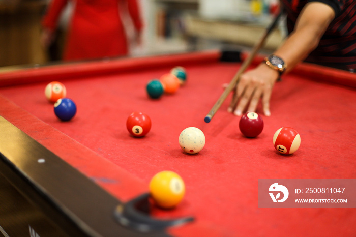 Close up of a man’s hand  preparing to shoot the white ball with a complete set of pool balls