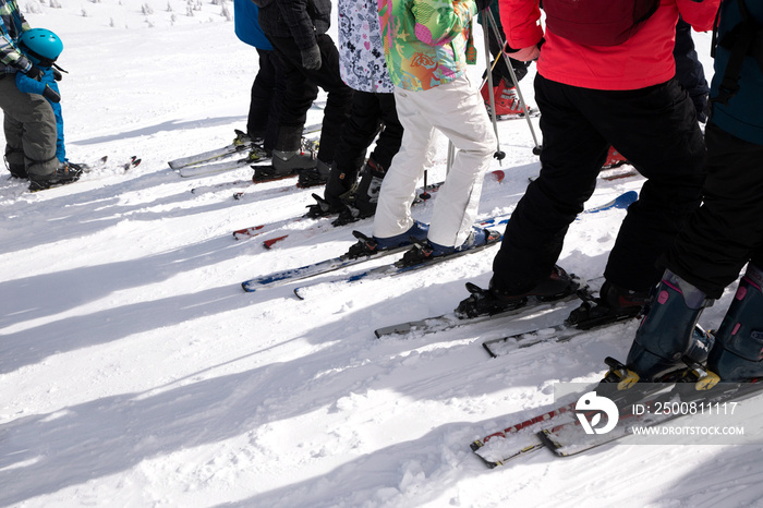 group of unrecognizable skiers standing in a row before the start of the descent from the snowy slope. Safety briefing, ski school. winter hobby, outdoor activities