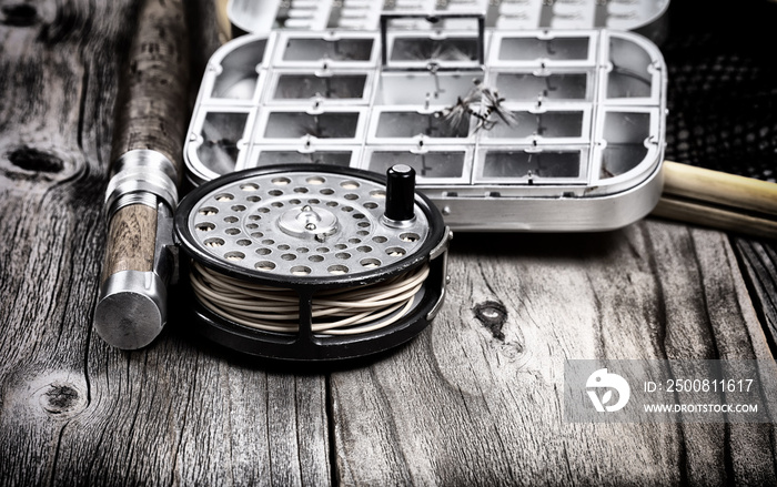 Antique vintage fly fishing reel and gear on rustic wooden background