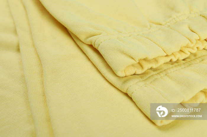 Folded yellow sweatpants on whole background, close up