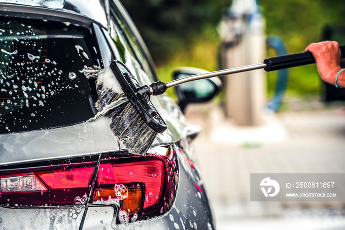 Manual car wash with white soap, foam on the body. Washing Car Using High Pressure Water.