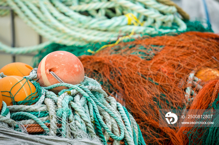 Many fishing nets and floats, stacked on a wooden dock. Fisheries, fishing. Fishing industry. In the distance is a fishing ship, boat. Background.