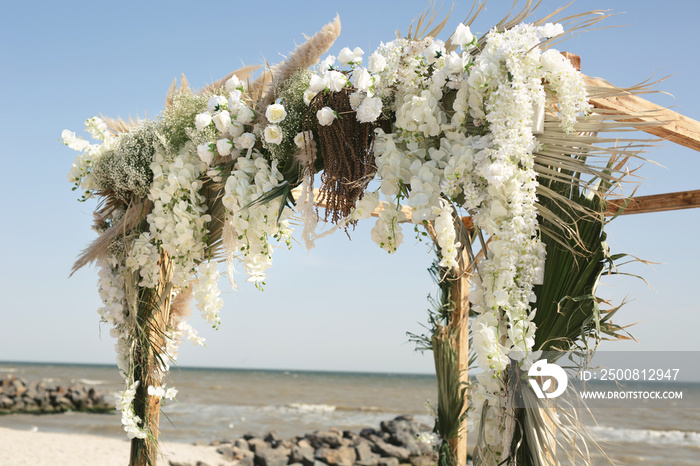 Outdoor area for beach ceremonies with sea view, white chairs, flower arch on a sunny day