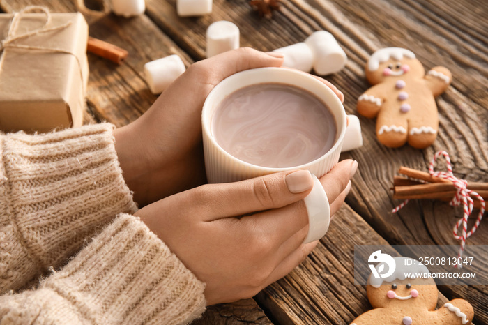 Female hands with cup of cacao on wooden table, closeup