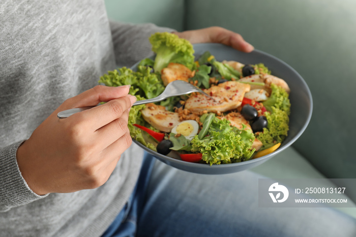 Woman eating tasty chicken salad at home, closeup