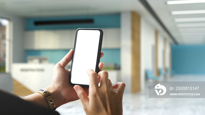 A female hands using a mobile phone over blurred hospital or clinic reception room background.