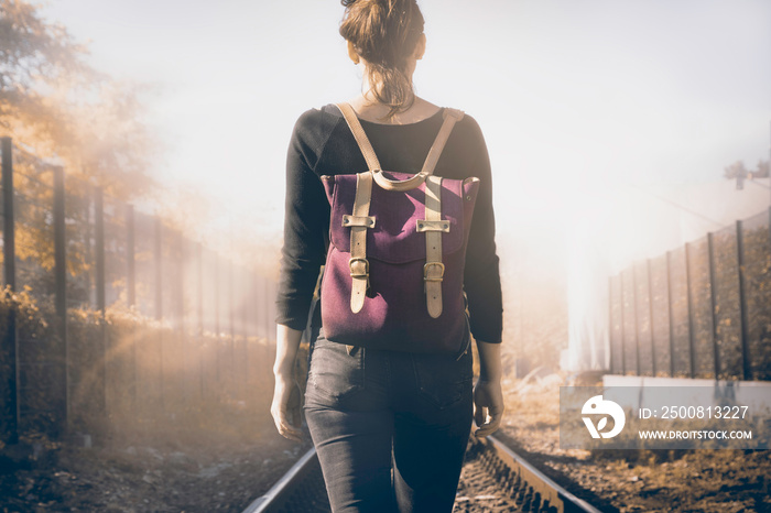 Traveler girl walking on railway tracks.