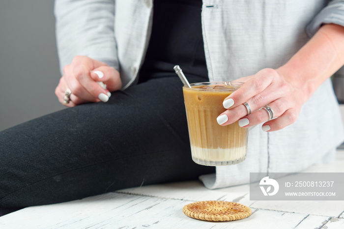 Close up of female sitting on table with hands holding cup of cold milky coffee, lifestyle of adult business woman in the weekend activity relaxing with the coffee drinking concept.